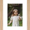 "Framed photo of a young girl holding a flower in an outdoor setting. "