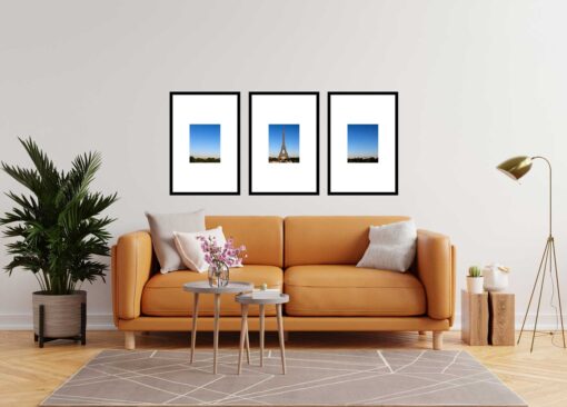 Living room with orange sofa and three framed Eiffel Tower photos on the wall.