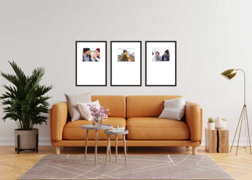 Modern living room with an orange sofa, three framed pictures on the wall, a floor lamp, and a potted plant.